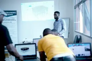 Structural engineering instructor leading a ProtaStructure software training session, displaying a 3D structural model on a projector screen in a classroom.